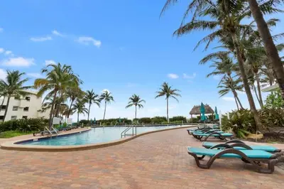 a resort swimming pool with chaise lounges and palm trees at Alquiler temporario Miami in Hollywood
