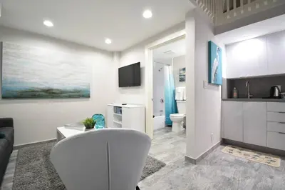 a white living room with a couch and a kitchen at Lofted Apt wQueen Loft Nook steps to Beach in Hollywood