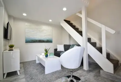 a living room with a white chair and stairs at Modern loft wqueen bed steps to beach in Hollywood
