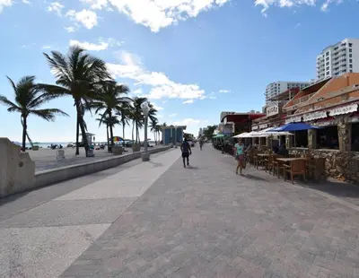 a person walking down a sidewalk next to the beach at Modern Loft wQueen Loft Steps to Beach in Hollywood