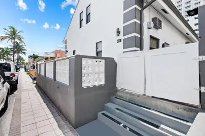 a white building with a gate and stairs on a sidewalk at Loft wqueen bed steps to Hollywood Beach in Hollywood