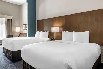 two beds in a hotel room with white sheets at Comfort Suites Fort Lauderdale Airport & Cruise Port in Dania Beach