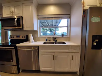 a kitchen with white cabinets and a sink and a window at Lakefront Vacation Home - Sleeps 8 in Davie