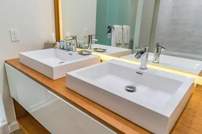 a white bathroom with two sinks and a mirror at Maritime Hotel Fort Lauderdale Airport & Cruiseport in Fort Lauderdale