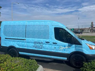 a blue van parked in a parking lot at Signature Inn Miami in Miami