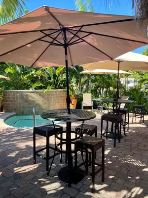 a table and chairs under an umbrella next to a pool at The Cabanas Guesthouse & Spa - Gay Resort catering to Gay Men in Fort Lauderdale