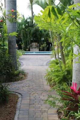 a brick walkway through a garden with palm trees at The Cabanas Guesthouse & Spa - Gay Resort catering to Gay Men in Fort Lauderdale