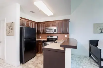 a kitchen with wooden cabinets and a black refrigerator at New Point Miami Beach Apartments in Miami Beach