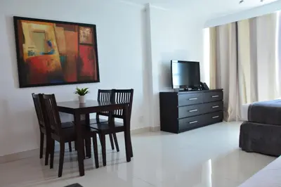 a dining room with a table and chairs and a television at New Point Miami Beach Apartments in Miami Beach