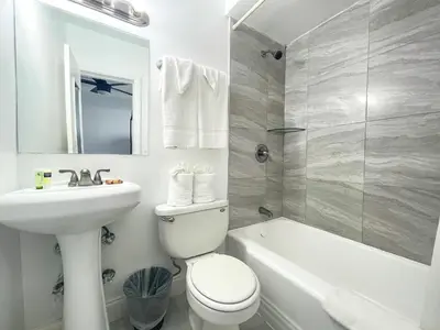 a white bathroom with a sink and a toilet and a tub at Hollywood Beach Hotels in Hollywood