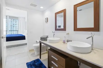 a bathroom with two sinks and a toilet and a mirror at Icon Brickell Residences in Miami