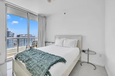 a white bedroom with a bed and a large window at Icon Brickell Residences in Miami
