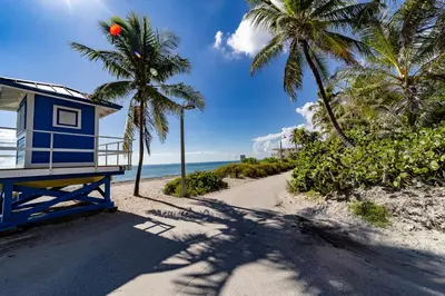 a blue house on a beach with palm trees at The Desoto - Oceanview Inn in Hollywood