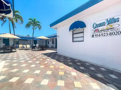 a white building with a patio with tables and umbrellas at Ocean Villas in Hollywood