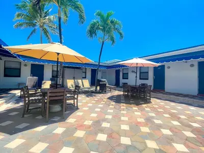 a patio with tables and umbrellas and palm trees at Ocean Villas in Hollywood