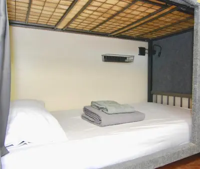 a white bed with a pile of towels on it at Sheridan Hostel in Dania Beach