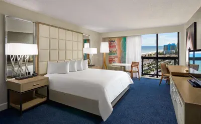 a hotel room with a bed and a desk and a room with a view at Bahia Mar Fort Lauderdale Beach - DoubleTree by Hilton in Fort Lauderdale