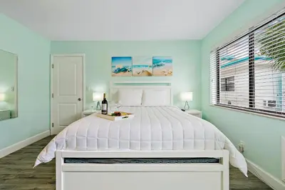 a bedroom with a white bed with a bottle of wine at Hollywood Beachside Boutique Suite in Hollywood