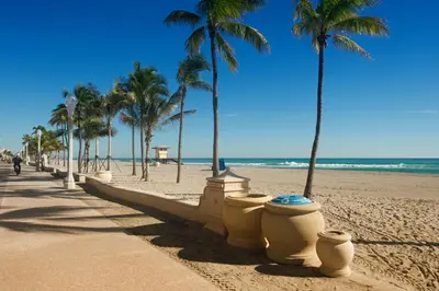 a sandy beach with palm trees and a sidewalk at Hollywood Beachside Boutique Suite in Hollywood