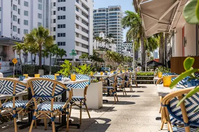 an outdoor restaurant with tables and chairs and palm trees at Hotel Continental Miami Beach, Tapestry Collection by Hilton in Miami Beach