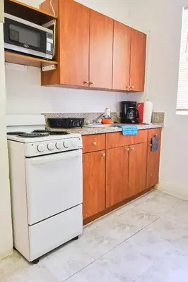 a kitchen with a white stove and wooden cabinets at The Marlin Rooster Apartments in Miami