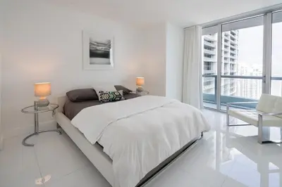 a white bedroom with a large bed and a window at ICON Brickell residences in Miami