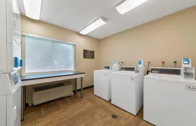 a laundry room with three machines and a window at Extended Stay America Premier Suites - Miami - Airport - Miami Springs in Miami