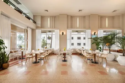 a restaurant with tables and chairs and windows at Eurostars Winter Haven Miami Beach in Miami Beach
