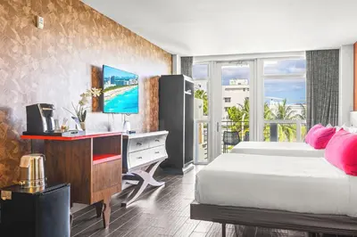 a bedroom with a bed and a desk with a computer at The Fairwind Hotel in Miami Beach
