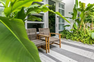two wicker chairs sitting on a porch with plants at The Fairwind Hotel in Miami Beach