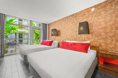 two beds in a hotel room with red pillows at The Fairwind Hotel in Miami Beach
