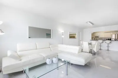 a white living room with a white couch and a glass table at Ocean Reserve Sunny Isles in Miami Beach
