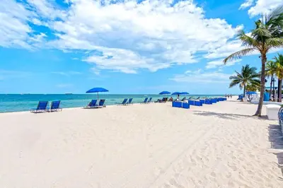 a beach with chairs and umbrellas and the ocean at Departamento en Tiffany House Fort Lauderdale beach Miami in Fort Lauderdale