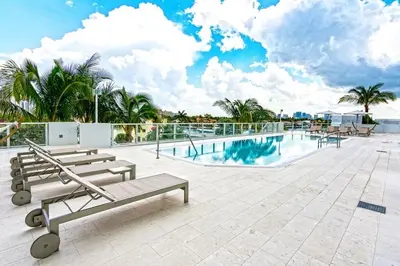a swimming pool with benches and palm trees on a building at Departamento en Tiffany House Fort Lauderdale beach Miami in Fort Lauderdale