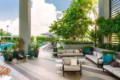 an outdoor patio with couches and chairs and a pool at Hyde Suites Midtown Miami in Miami