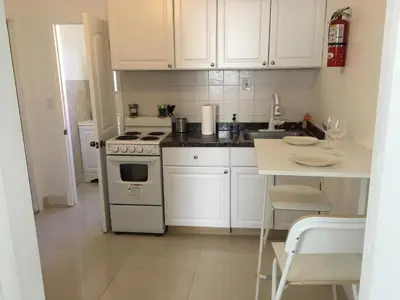 a kitchen with white cabinets and a stove and a table at Close to Everything Miami in Miami