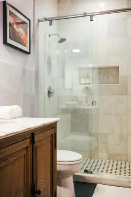 a bathroom with a toilet and a glass shower at Renovated Historic Coconut Grove Cottage Home in Miami