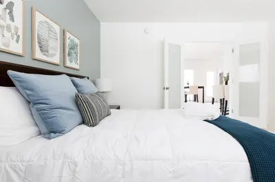 a bedroom with a large white bed with blue pillows at Lovely apartment on the canal with a pool in Fort Lauderdale