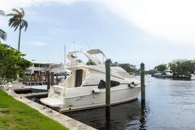 a white boat docked at a dock in the water at Lovely apartment on the canal with a pool in Fort Lauderdale