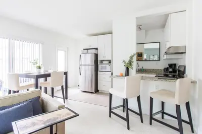 a kitchen with white cabinets and a table and chairs at Lovely apartment on the canal with a pool in Fort Lauderdale