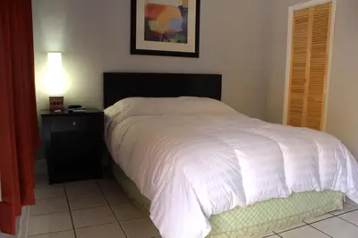 a bedroom with a bed with a white bedspread and a lamp at Ramona Motel in Miami