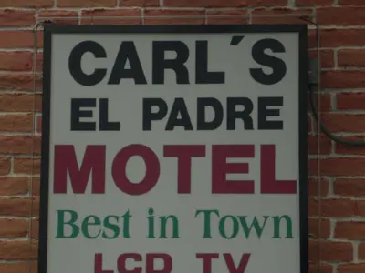 a sign hanging on a brick wall at Carl's El Padre Motel in Miami