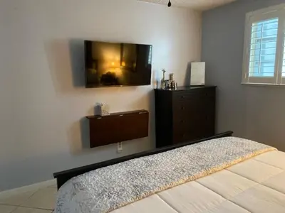 a bedroom with a bed and a tv on the wall at Modern 2/1 Apt near Midtown and Beaches in Miami