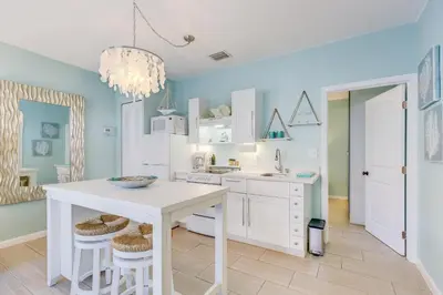 a kitchen with blue walls and white cabinets and a table at A Suite Retreat in Miami