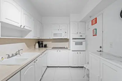 a white kitchen with white cabinets and a sink at Great Apartment with beach access in Hollywood