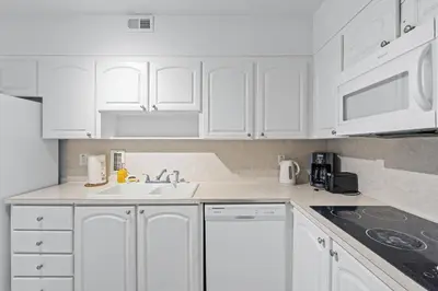 a white kitchen with white cabinets and a sink at Great Apartment with beach access in Hollywood