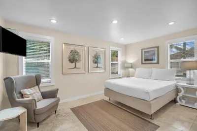 a bedroom with a bed and a chair and a television at Grove Bay Bungalow - 2/2 Gated Cottage-Walk to Bay in Miami