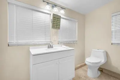 a white bathroom with a toilet and a sink at Grove Bay Bungalow - 2/2 Gated Cottage-Walk to Bay in Miami