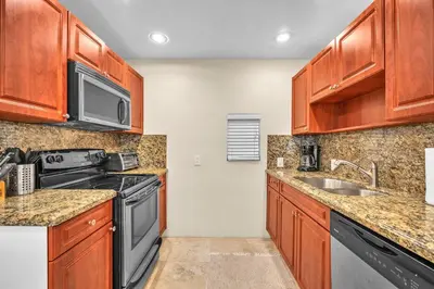 a kitchen with wooden cabinets and a stove and a sink at Grove Bay Bungalow - 2/2 Gated Cottage-Walk to Bay in Miami