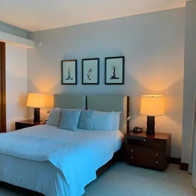 a bedroom with a blue bed with two lamps and three pictures at One Bal Harbour Ritz Bal Harbour in Miami Beach